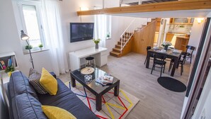 A modern apartment with a living room, dining area, kitchen, and a staircase leading to an upper level. - Furioso Apartments (Split)