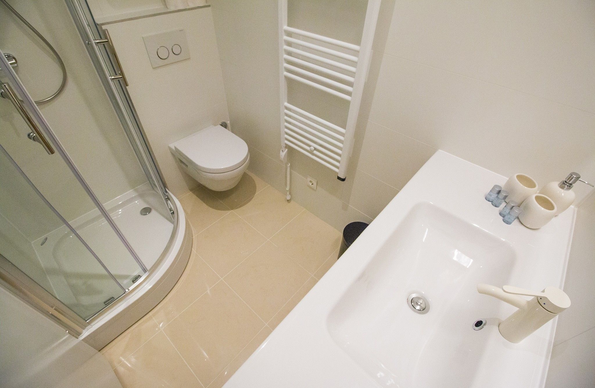 Een badkamer met een douchecabine van glas, een toilet en een wastafel met toiletartikelen.