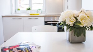 A kitchen with white cabinets, a white countertop, and a vase with white flowers on the table. - Furioso Apartments (Split)