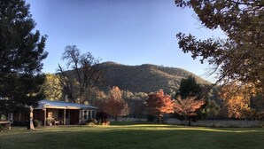 A house with a porch and a lawn in front. - Historic Miners Cottage on Howqua River (Howqua)