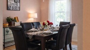A dining room with a chandelier, a table set for four, and a view of the outdoors through a window. - 3.5 miles to Washington DC- Family Size Spacious 4BDR + Parking (Arlington)