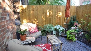A patio with a brick wall, a wooden fence, and various potted plants. - 3.5 miles to Washington DC- Family Size Spacious 4BDR + Parking (Arlington)