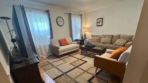A living room with a sofa, armchair, coffee table, and a rug. - 3.5 miles to Washington DC- Family Size Spacious 4BDR + Parking (Arlington)