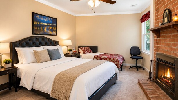 A bedroom with a large bed, a smaller bed, a desk, a chair, a fireplace, and a ceiling fan. - 3.5 miles to Washington DC- Family Size Spacious 4BDR + Parking (Arlington)