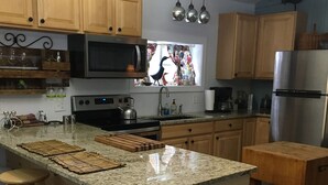 Una cocina con gabinetes de madera, encimera de granito, refrigerador de acero inoxidable y una ventana con vista a pájaros.