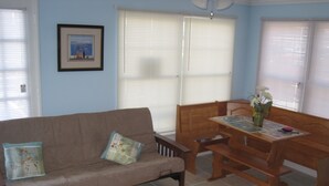 Ein Wohnzimmer mit braunem Sofa, einem Holzesstisch und einem gerahmten Bild an der Wand.