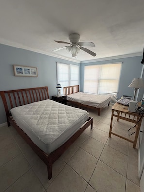 A bedroom with two beds, a ceiling fan, and a bedside table with a lamp. - Beachfront Condo (Wildwood)