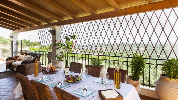 A terrace with wicker furniture, a table set for dining, and potted plants. - SUNLIGHT VILLA WITH PRIVATE POOL  FOR FAMILIES AND FRIENDS TO ENJOY (Myrtia)