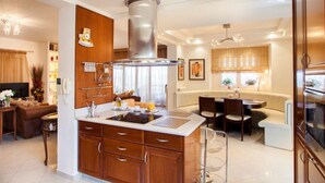 A modern kitchen with a central island, wooden cabinets, and a stainless steel range hood. - SUNLIGHT VILLA WITH PRIVATE POOL  FOR FAMILIES AND FRIENDS TO ENJOY (Myrtia)