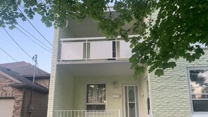 A two-story house with a front porch, a garage door, and a brick wall. - Be At Home Away From Home II (Welland)
