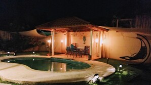 A pool area with a covered seating area and a dining table.
