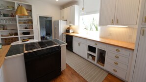 Une cuisine moderne avec des meubles blancs, une cuisinière noire et un plan de travail en bois.