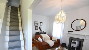 Un salon avec un escalier, une cheminée et un lustre.