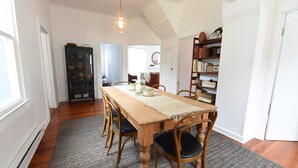 Un espace repas comprenant une table en bois, des chaises, un tapis et un luminaire suspendu.