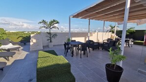 A rooftop patio with outdoor furniture, a covered seating area, and potted plants. - Suite Riviera 211 *Rooftop Pool* (Playa del Carmen)