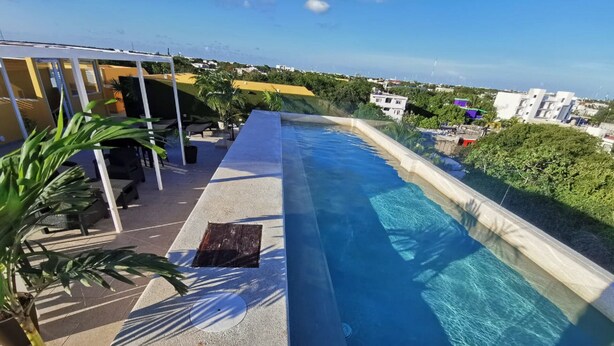 A rooftop infinity pool with a clear view of the cityscape in the background. - Suite Riviera 211 *Rooftop Pool* (Playa del Carmen)