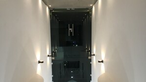 A corridor with a central spiral staircase, flanked by walls with recessed lighting and a glass partition. - Suite Riviera 211 *Rooftop Pool* (Playa del Carmen)