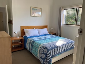 A neatly made bed with a patterned bedspread, a bedside lamp, and a nightstand. - Unit 3 Beachside units.  Pambula Beach (Pambula Beach)