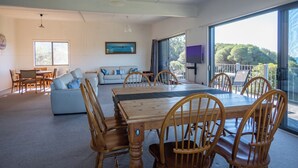 A spacious living area with a dining table, wooden chairs, a sofa, and a TV. - Unit 3 Beachside units.  Pambula Beach (Pambula Beach)