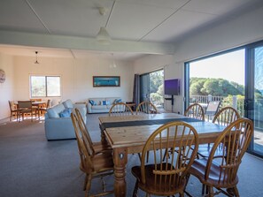 A spacious living area with a dining table, wooden chairs, a sofa, and a TV. - Unit 3 Beachside units.  Pambula Beach (Pambula Beach)