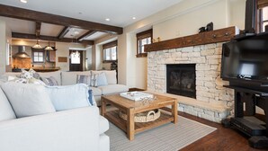 A spacious living room with a stone fireplace, a large TV, and a cozy seating area.