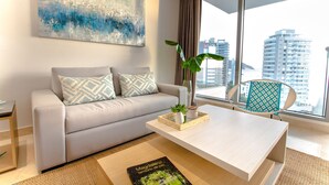 Un salon moderne avec un canapé, une table basse et une vue sur de hauts immeubles.