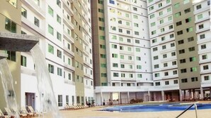 Un hotel moderno con zona de piscina central, varios balcones y una cascada.