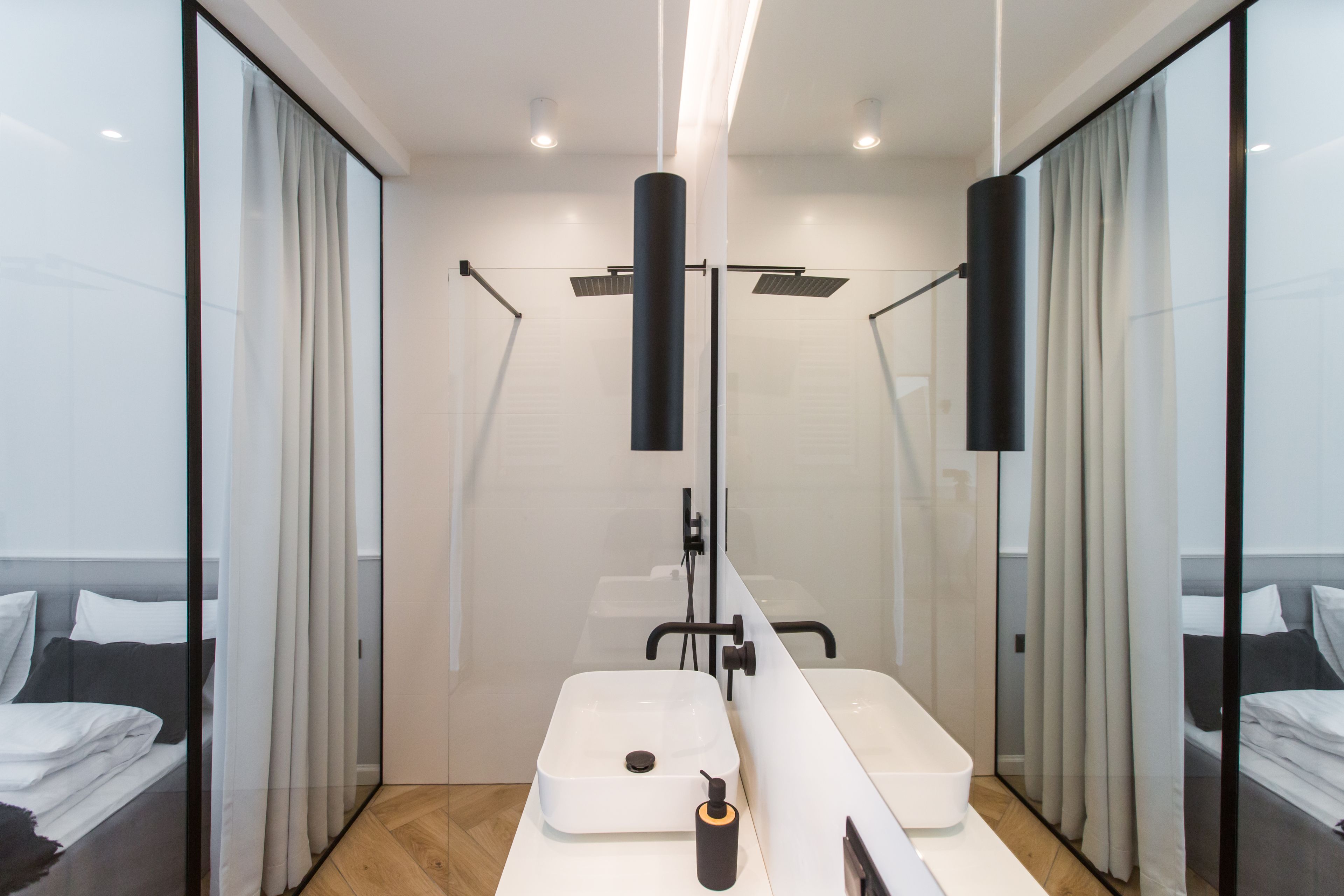 A modern bathroom with a large mirror, two sinks, and a shower area.