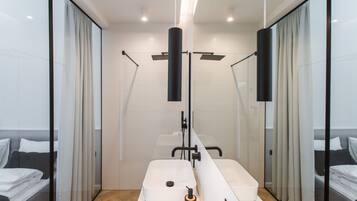 A modern bathroom with a large mirror, two sinks, and a shower area.