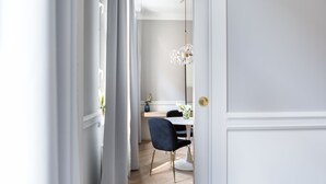 Uma área de jantar moderna com uma mesa branca, cadeiras escuras e um abajur alto.