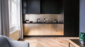 Cozinha moderna com bancada preta, eletrodomésticos de aço inoxidável e uma janela com cortinas.
