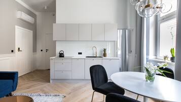 Cozinha moderna com armários brancos, uma mesa de jantar redonda e uma cadeira azul.