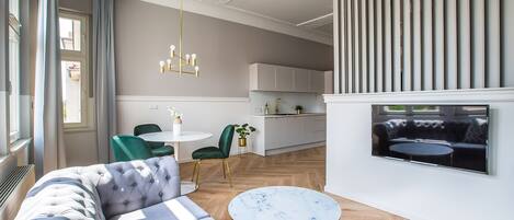 A modern living room with a sofa, a round coffee table, and a dining area with chairs.
