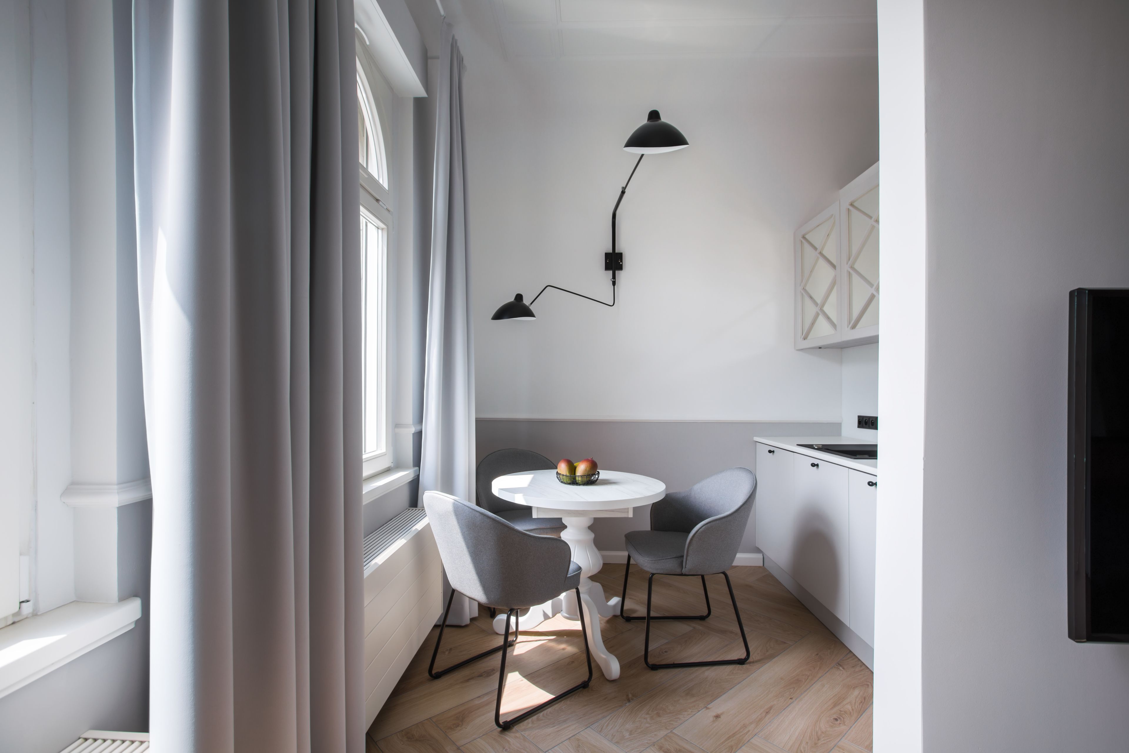Een kleine keuken met een eethoek, met een witte tafel, twee stoelen en een schaal fruit.