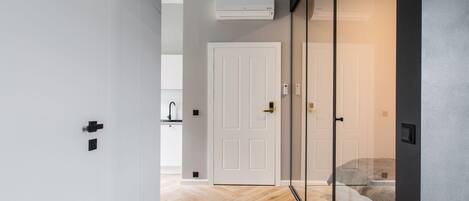 A modern interior with a wooden floor, a white door, and a glass partition.