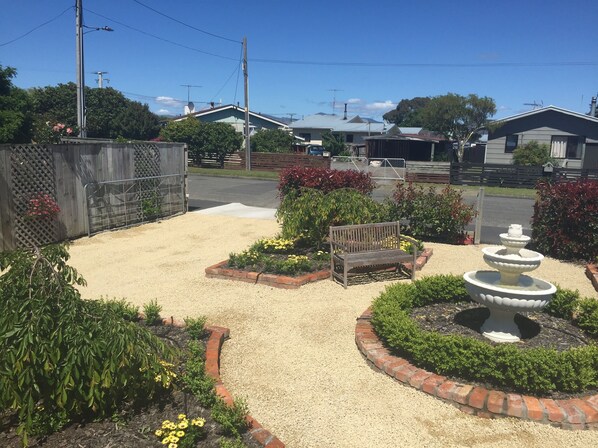 A garden with a bench, a fountain, and various plants.
