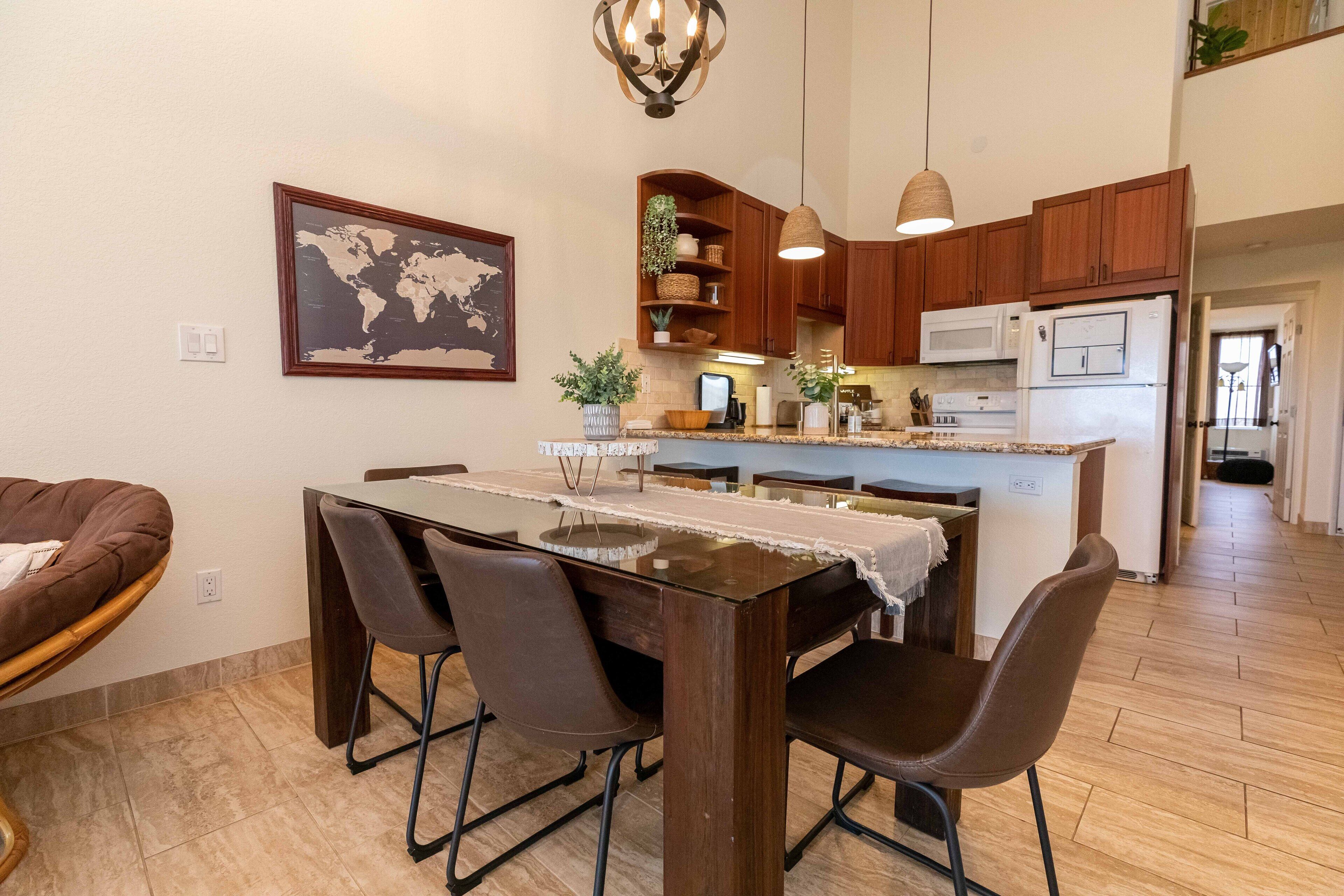 A modern kitchen with wooden cabinets, a central island, and a dining area with a table and chairs.