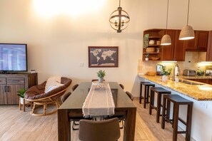 Uma cozinha moderna com armários de madeira, bancada de granito e um espaço de refeições com mesa e cadeiras.