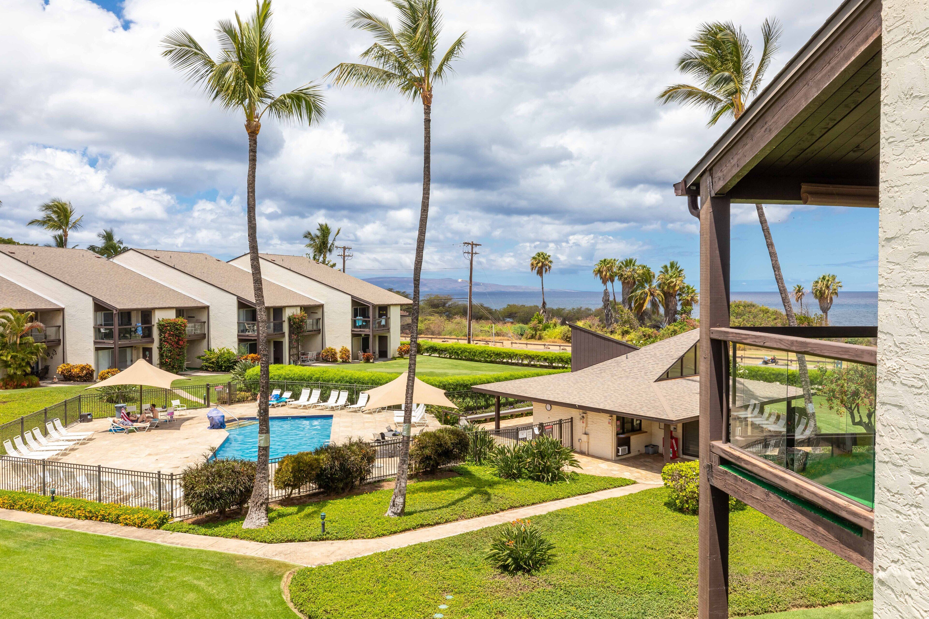 A resort with a swimming pool, palm trees, and a view of the ocean.