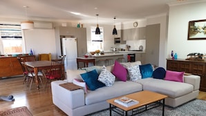 A modern living room with a sofa, coffee table, and dining area. - Victorian Home in Heart of Orange - Pet Friendly (Orange)