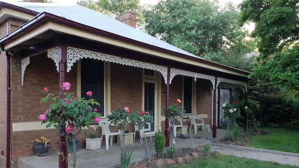 A brick building with a porch, white chairs, and potted plants. - Victorian Home in Heart of Orange - Pet Friendly (Orange)