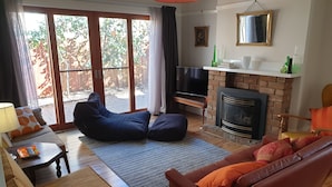 A living room with a sofa, a bean bag, a fireplace, a TV, and a dining area with a table and chairs. - Victorian Home in Heart of Orange - Pet Friendly (Orange)