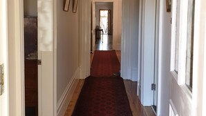 A hallway with a red patterned carpet, white walls, and wooden floors. - Victorian Home in Heart of Orange - Pet Friendly (Orange)