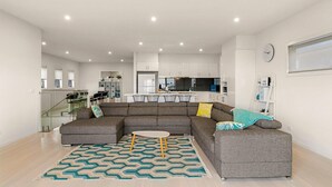 Een moderne woonkamer met een hoekbank, een klein bijzettafeltje en een kamerbreed tapijt.