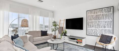 Una sala de estar moderna con un sofá, una mesa de centro y un televisor sobre un mueble.