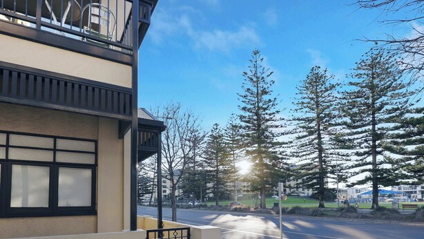 A multi-story building with a balcony, a clear sky, and trees in the background.
