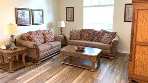 A living room with two sofas, a coffee table, a lamp, and framed pictures on the wall.