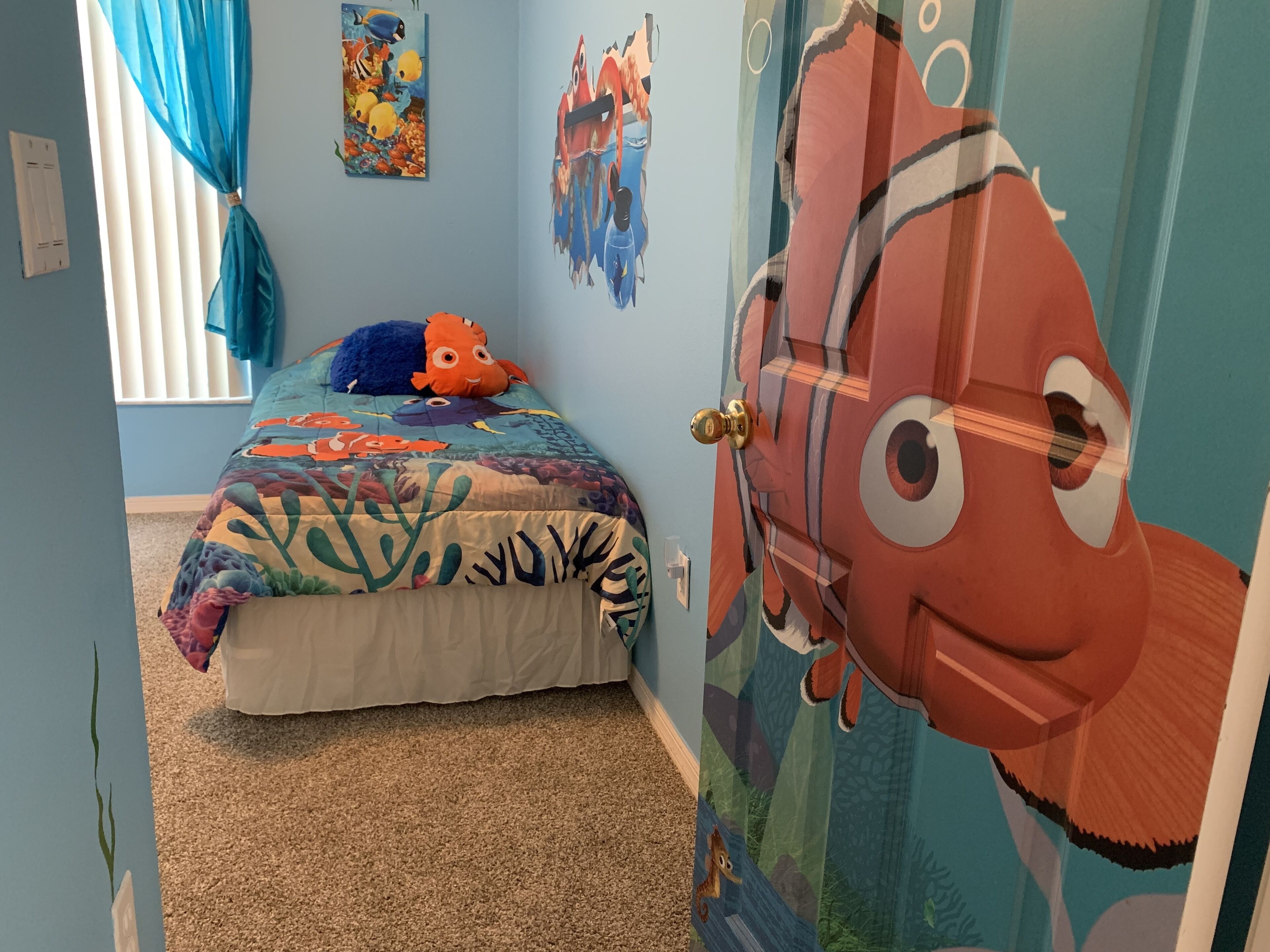 A child's bedroom with a bed, a plush toy, and a mural of a fish on the door.