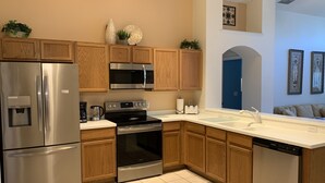 A modern kitchen with stainless steel appliances, wooden cabinets, and a white countertop.