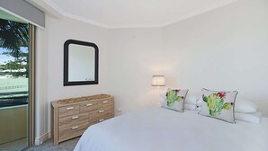 Une chambre à coucher avec un lit, une commode, un miroir et une lampe.